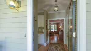 A hallway with a patterned rug, wooden floors, and a ceiling light fixture.