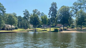 A serene lakeside view with a gazebo, a well-maintained lawn, and tall trees.