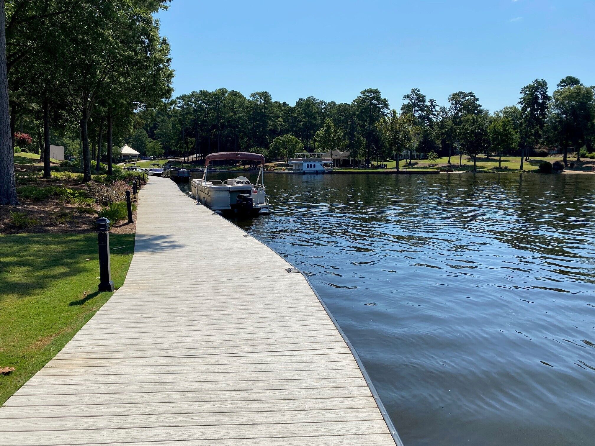 A wooden dock extending into a calm body of water, with a rowboat docked at the end.