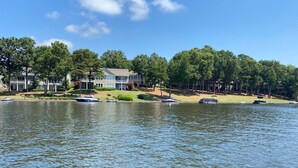 A lakeside view with a row of houses, boats, and trees.