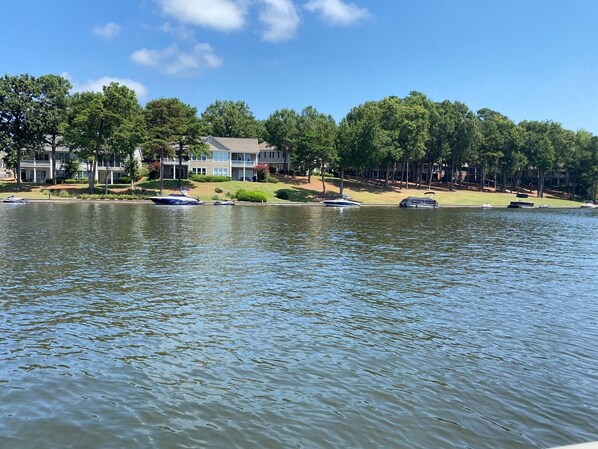 A lakeside view with a row of houses, boats, and trees.