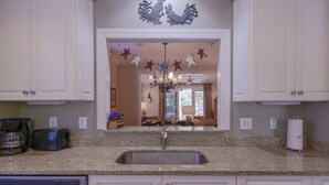 A kitchen with white cabinets, a granite countertop, a stainless steel sink, a coffee maker, and a toaster.
