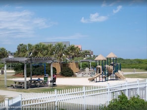A playground with a kiddy pool, picnic tables, and a covered seating area.