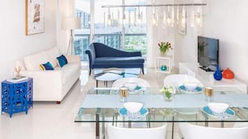 Un salon moderne avec une table à manger en verre, des canapés blancs et un canapé bleu.