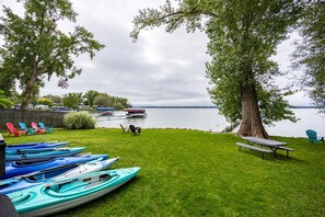 A lakeside property with kayaks, chairs, and a picnic table.