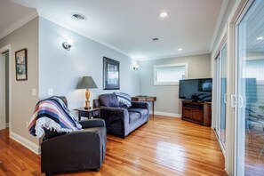 A living room with a sofa, armchair, TV stand, and a lamp.