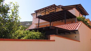 A multi-story building with a flat roof, a balcony, and a red-tiled roof section. - Appartamenti Montecristo e Pianosa (Campo nell'Elba)