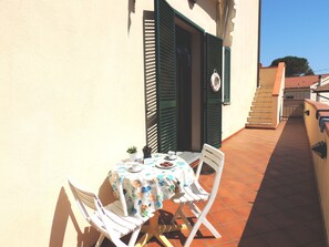 A small outdoor table with a tablecloth, two white chairs, and a potted plant. - Appartamenti Montecristo e Pianosa (Campo nell'Elba)
