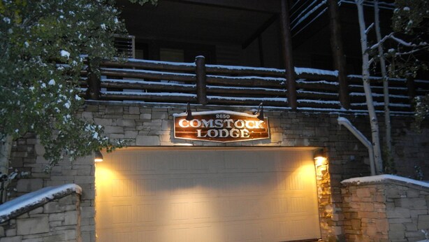 Une entrée enneigée menant à un chalet, sur laquelle on peut lire l’inscription « COMSTOCK LODGE ».