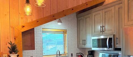 Una cocina con una isla grande, armarios de madera, estufa de acero inoxidable e iluminación colgante.