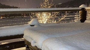 Un espace extérieur enneigé, doté d’une rambarde en bois et d’escaliers.