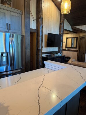 A kitchen with a marble countertop, stainless steel appliances, wooden walls, and a mounted television. - Cozy Ski Chalet,  Mountain Views and short walk to base of Deer Valley! (Park City)