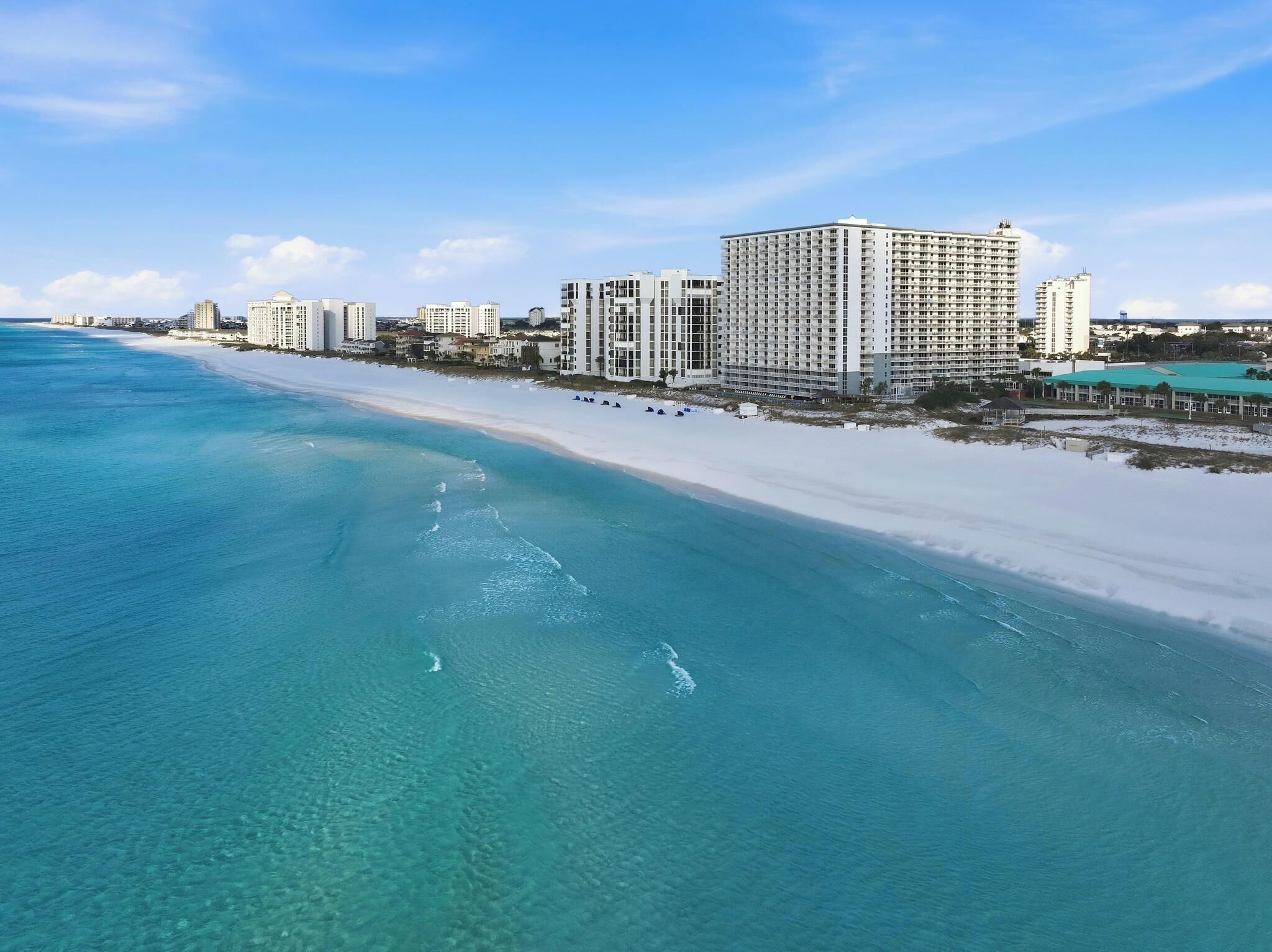 Ett hotell vid kusten med utsikt över stranden, flera höga byggnader och en sandstrand.