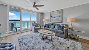 A modern living room with a balcony, a ceiling fan, and a large abstract painting.