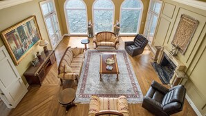 A spacious living room with a large window, a fireplace, and a classic sofa set. - The Retreat with  Wilson Dam view & Water Aces (Florence)