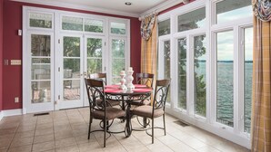 A dining area with a table set for four, surrounded by chairs, and large windows offering a view of a body of water. - The Retreat with  Wilson Dam view & Water Aces (Florence)