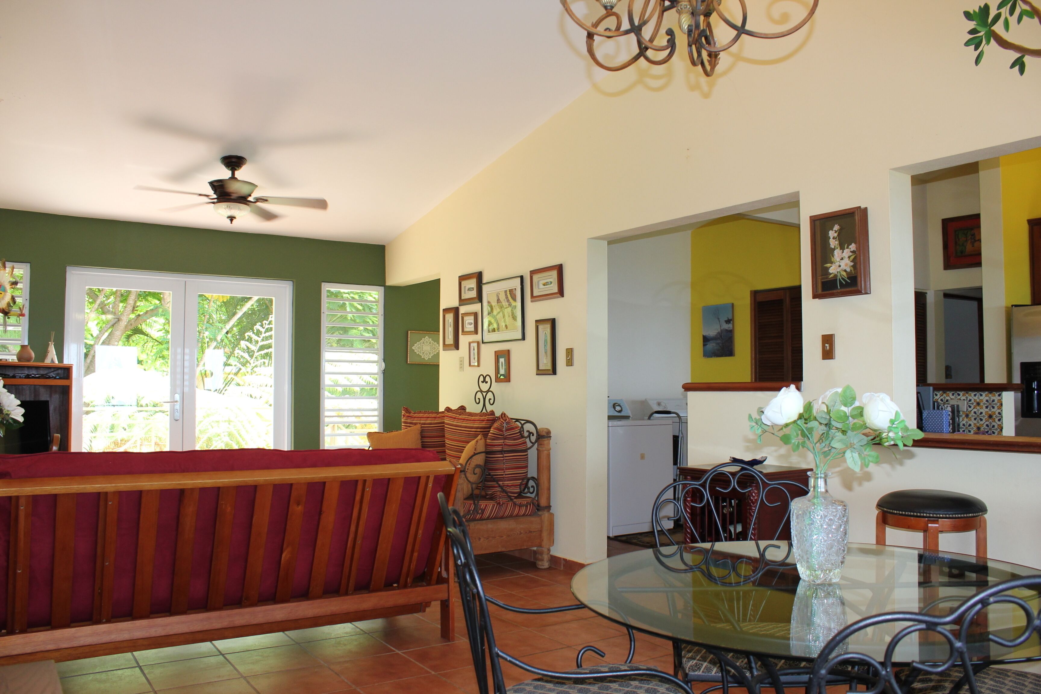 Una sala de estar con una mesa de vidrio, un sofá y un ventilador de techo.