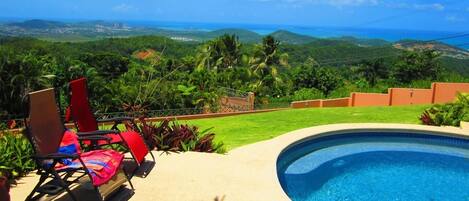 A swimming pool with a view of a lush landscape and distant hills.