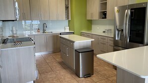 Una cucina moderna con mobili chiari in legno, un frigorifero in acciaio inossidabile e una lavastoviglie.
