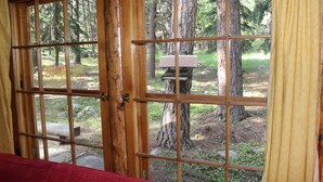 A wooden cabin with a large window revealing a forested area outside. - Storybook Cottage in the Heart of the Big Horn Mountains (Story)
