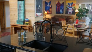 Une cuisine dotée d’un évier noir, de meubles en bois et d’un coin repas avec une table et des chaises.