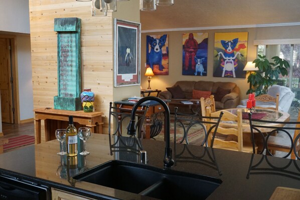 A kitchen with a black sink, wooden cabinets, and a dining area with a table and chairs. - Sandia Heights Getaway_VIEWS, UPSCALE, 3BR (Albuquerque)