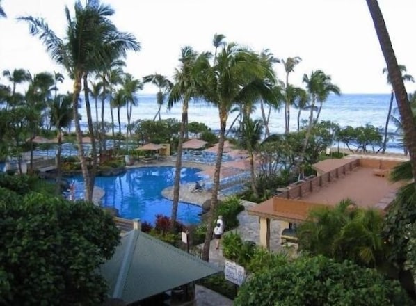 Zona de piscina con palmeras y vistas al océano.