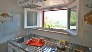 A kitchen with a window, stainless steel sink, and a kettle on the counter. - Villa Porticciolo (Rio)