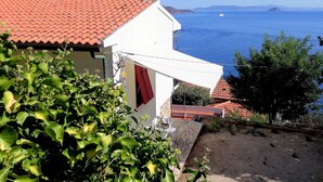 A coastal house with a red-tiled roof, white walls, and a view of the sea. - Villa Porticciolo (Rio)