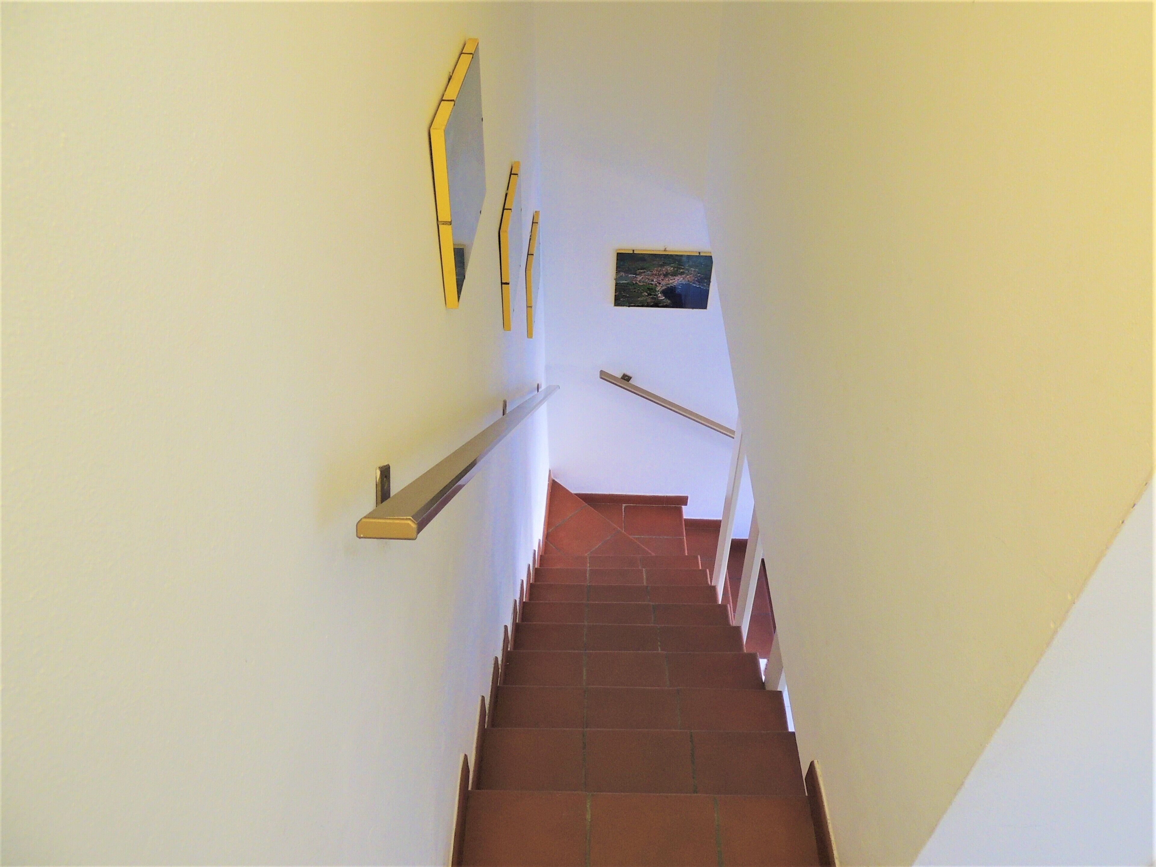 A staircase with a handrail and a picture on the wall.