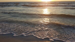 A beach with waves and the sun setting in the background. - Bright Corner Condo with Lake-View Lanai - Pool, 5 min to Bonita Beach (Bonita Springs)