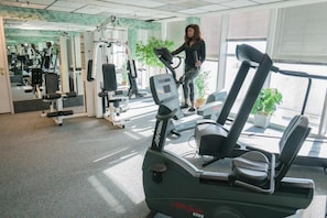 Academia com máquinas de cardio, aparelhos de musculação e um espelho grande.
