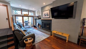 A living room with a leather sofa, a fireplace, a television, and a large window. - Luxury Condo w/ FREE WiFi, Parking, Heated Pool, Hot Tubs, Skier Shuttles (Avon)