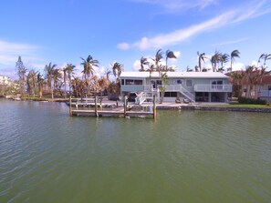 A waterfront property with a dock, a covered outdoor seating area, and a two-story building with a balcony.