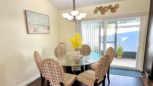 A dining area with a glass table, patterned chairs, a chandelier, and a painting on the wall. - Beautifully, Renovated Home in Quiet Cul de Sac! Close to EVERYTHING!  (Oldsmar)