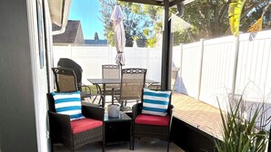 A covered patio area with a table and chairs, a potted plant, and a view of the backyard. - Beautifully, Renovated Home in Quiet Cul de Sac! Close to EVERYTHING!  (Oldsmar)