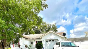 A white house with a garage, a driveway, and a white car parked in front. - Beautifully, Renovated Home in Quiet Cul de Sac! Close to EVERYTHING!  (Oldsmar)