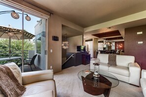 Una sala moderna con una mesa de centro de vidrio, un sofá blanco y un área de comedor con televisor.