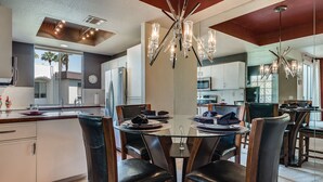 Una cucina moderna con un tavolo da pranzo in vetro, sedie in pelle scura e un lampadario originale.