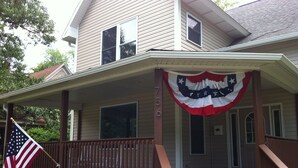 Ein zweistöckiges Haus mit Veranda, einer Flagge und einem Briefkasten.