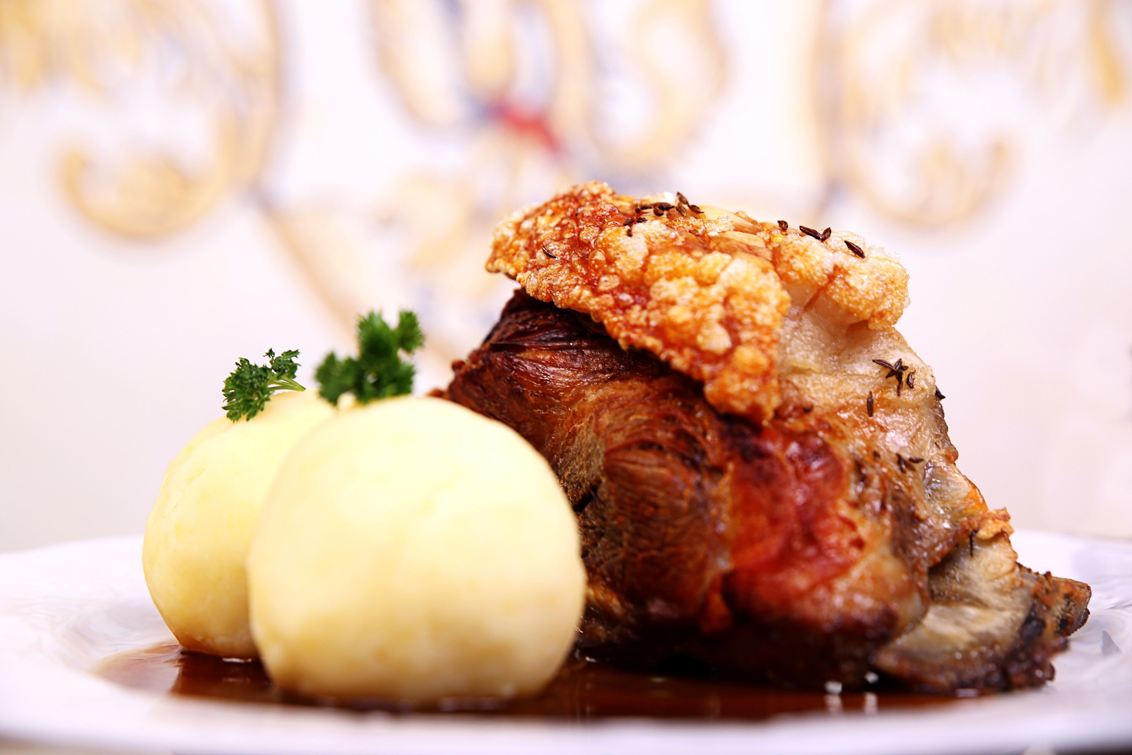 Um prato com carne assada, duas batatas cozidas e um guarnição de salsa.
