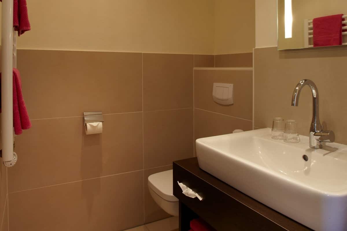 A bathroom with a white sink, a mirror, and a red towel rack.