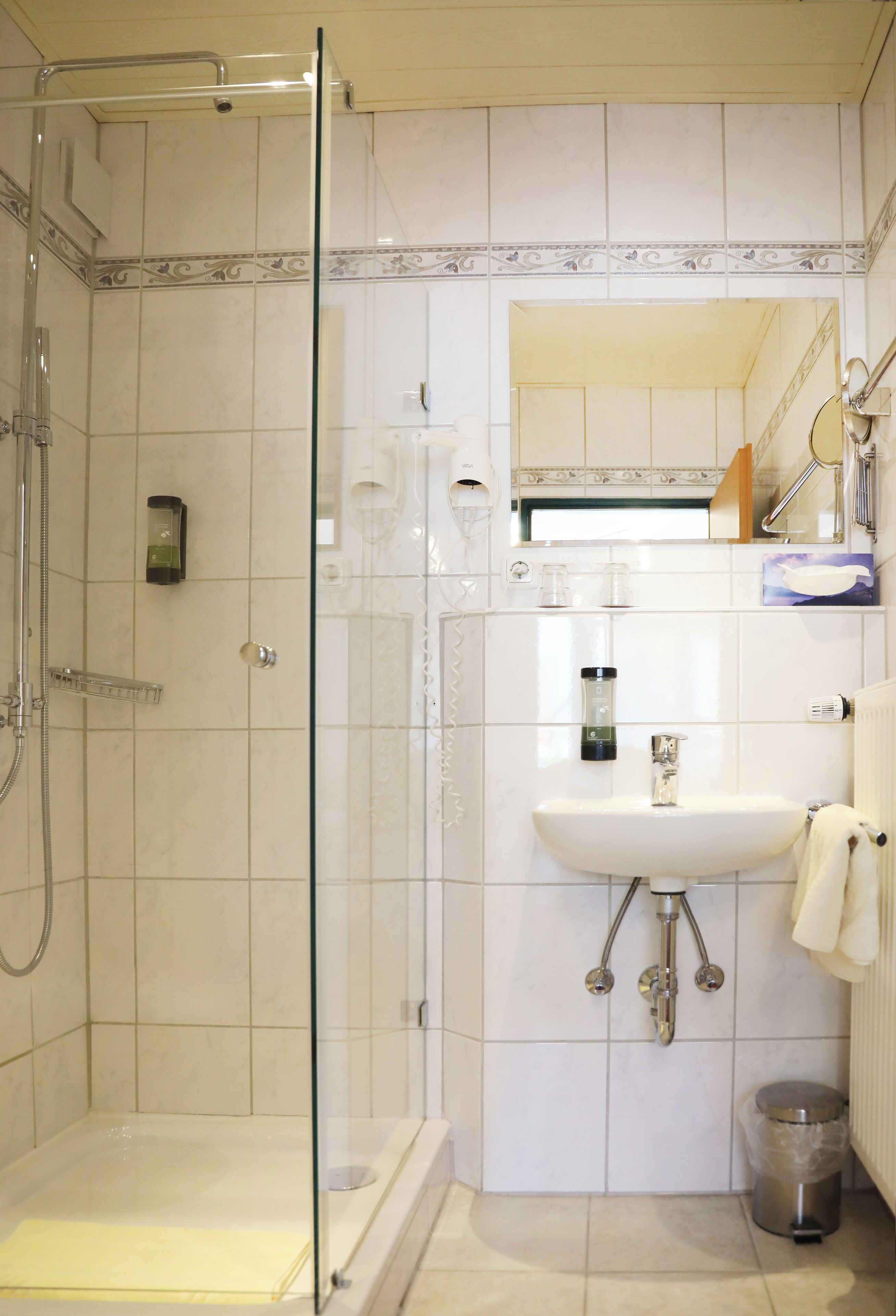 A bathroom with a glass-enclosed shower, a sink, and a toilet.