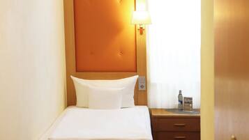 Une chambre d’hôtel avec un lit, une table de chevet, une lampe et une porte.
