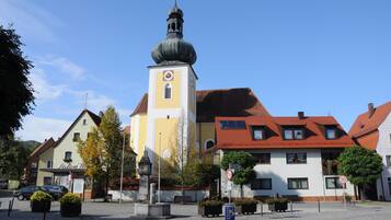 A town square with a church tower, benches, and a sign indicating a speed limit of 30.
