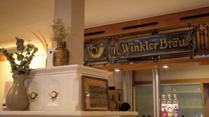 A reception area with a sign reading "Winkelbräu" and a display of liquor bottles. - Gasthof Zur Post (Königstein)