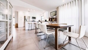 A modern kitchen with white cabinets, stainless steel appliances, and a central island with seating. - Beach Oasis  w/ screened in porch, incl beach gear, 15min walk to beach (Naples)