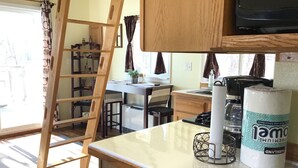 Una cucina compatta con una scala in legno, un tavolino e un frigorifero.