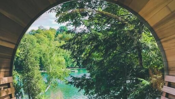 A wooden staircase leading to a circular viewing platform with benches, overlooking a lush green landscape and a body of water. - The Frontenac: A Lakeside Cabin Retreat with Sauna (Godfrey)