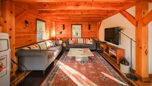 A cozy cabin interior with a sofa set, a coffee table, and a television. - The Frontenac: A Lakeside Cabin Retreat with Sauna (Godfrey)